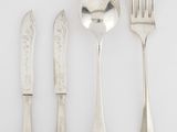 quatre fourchettes, une cuillère et un couteau posés sur un plan de travail blanc