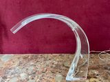 une sculpture en verre transparent posée sur une table avec un fond rouge