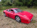 an image of a red sports car parked in a gravel lot