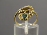 Gros plan sur une bague en or ornée d'une pierre verte