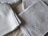 several folded napkins with embroidered monograms on them on a bed