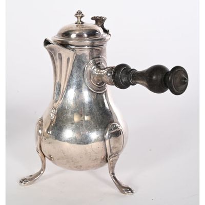 une cafetière en argent avec une poignée noire, posée sur un socle