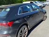 the rear of a black car is parked in a parking lot