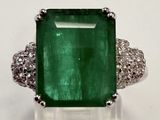 gros plan d'une bague avec une pierre verte entourée de diamants blancs