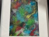 painting of a colorful abstract painting in a black frame on a table