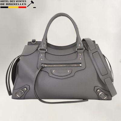 le grand sac gris est posé sur une surface blanche
