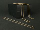 trois boîtes noires ornées de chaînes dorées sur fond noir