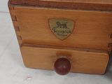 an old wooden box with a red lid sitting on top of a white table
