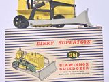 un petit bulldozer jaune en plastique posé sur une boîte