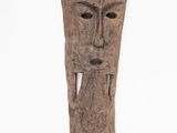 une sculpture sur bois représentant le visage d'un homme sur fond blanc