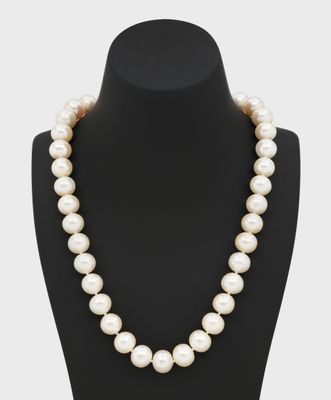 a white pearl necklace on a black mannequin
