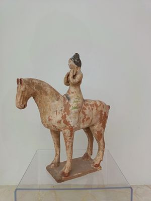 a statue of a woman riding a horse on a clear table