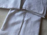 trois serviettes blanches posées sur un lit, ornées d'un monogramme