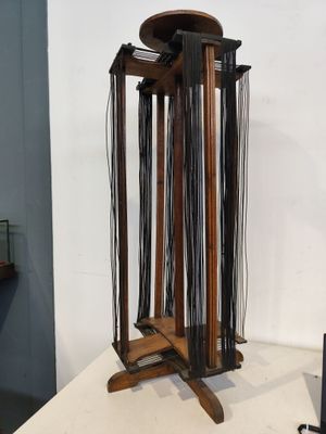 un support en bois auquel sont fixés plusieurs fils