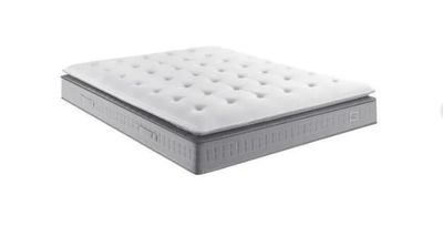 Le matelas est blanc et recouvert d'une housse blanche.