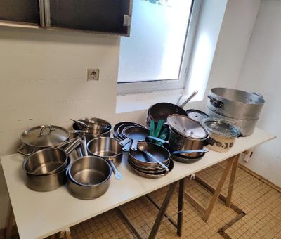 de nombreuses casseroles et poêles posées sur une table dans la cuisine