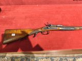 un vieux fusil est exposé dans une vitrine posée sur un tapis rouge