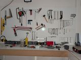 a workbench with many tools hanging on the wall