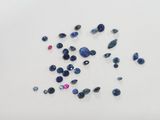 a bunch of blue and pink sapphires on a white surface