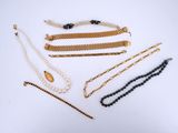 plusieurs types de colliers et de bracelets posés sur un fond blanc