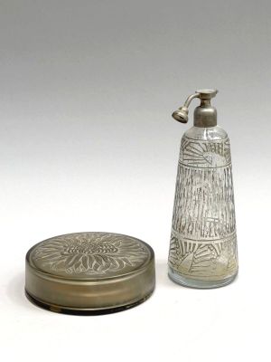 a glass bottle with a metal lid next to a small glass container