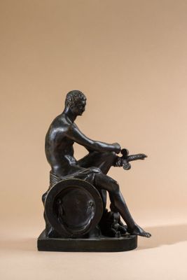 bronze statue of a man sitting on a barrel with a guitar