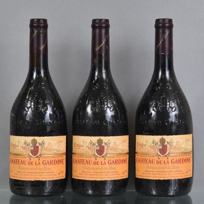 Trois bouteilles de vin sont alignées sur une table en verre