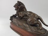 bronze statue of a lion on a wooden base on a white background