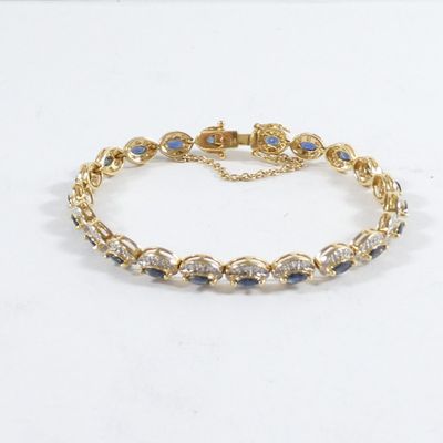 un gros plan sur un bracelet en or orné de pierres bleues et blanches
