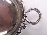 a silver bowl with a handle on a white surface