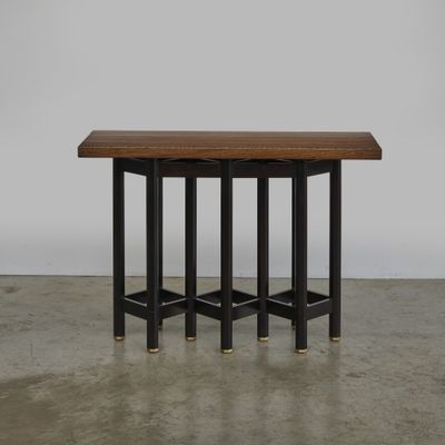 une table noire et en bois, à trois pieds, avec un plateau en bois