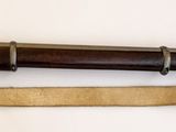 un pistolet très ancien avec une crosse en bois, posé sur une surface blanche