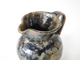 a blue and black vase with a handle on a white surface
