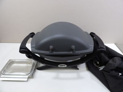 a grill with a lid on a table next to a bag