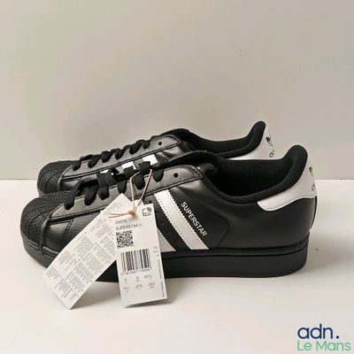 chaussures Adidas Superstar noires et blanches avec une étiquette de prix sur le côté
