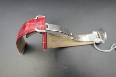 a red strap that is attached to a silver watch