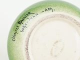 a green vase with writing on it sitting on a table