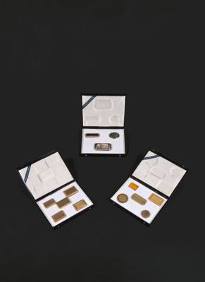 trois boîtes contenant différents types de maquillage sur une surface noire