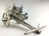 une maquette en métal argenté représentant une charrette sur laquelle est posé un oiseau