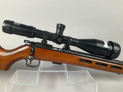 a close up of a rifle with a scope on a clear stand