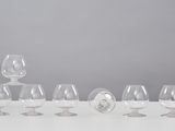six empty wine glasses lined up in a row on a white table