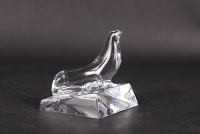a clear glass sculpture of a bird on a rock on a black surface