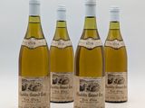 quatre bouteilles de vin sont alignées sur une surface blanche