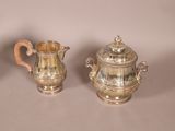 two silver teapots sitting next to each other on a table