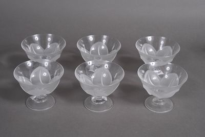 four clear glass bowls with a flower design on them on a gray surface