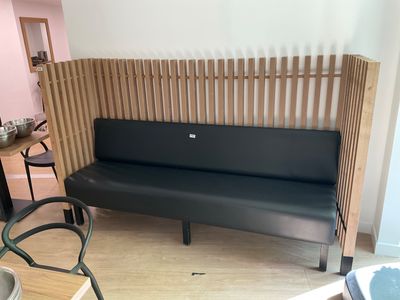 a black bench in the corner of a room with a table and chairs