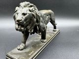 a bronze statue of a lion on a marble base