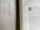 two open books on a table with a clock on it