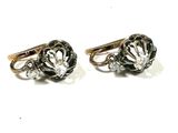 deux paires de boucles d'oreilles en forme de losange, noires et blanches, posées sur une surface blanche