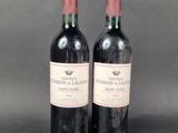 two bottles of red wine sitting next to each other on a table